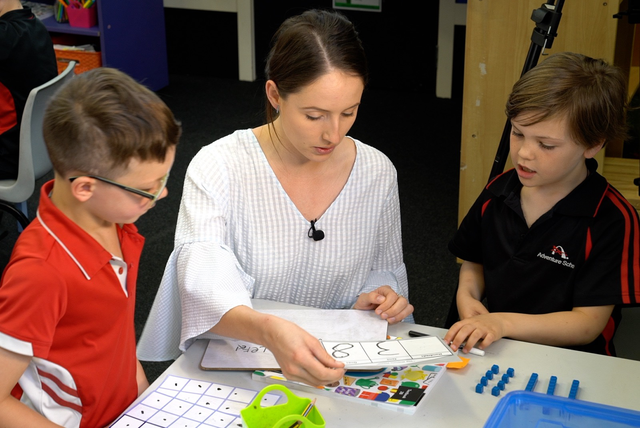 Teacher helping two pupils with maths.