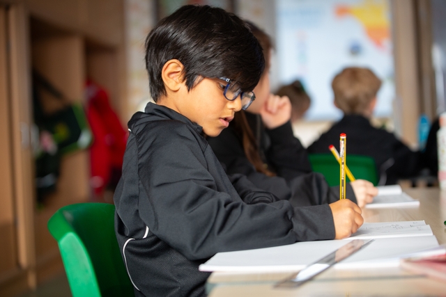 Young male student writing on paper with a pencil.