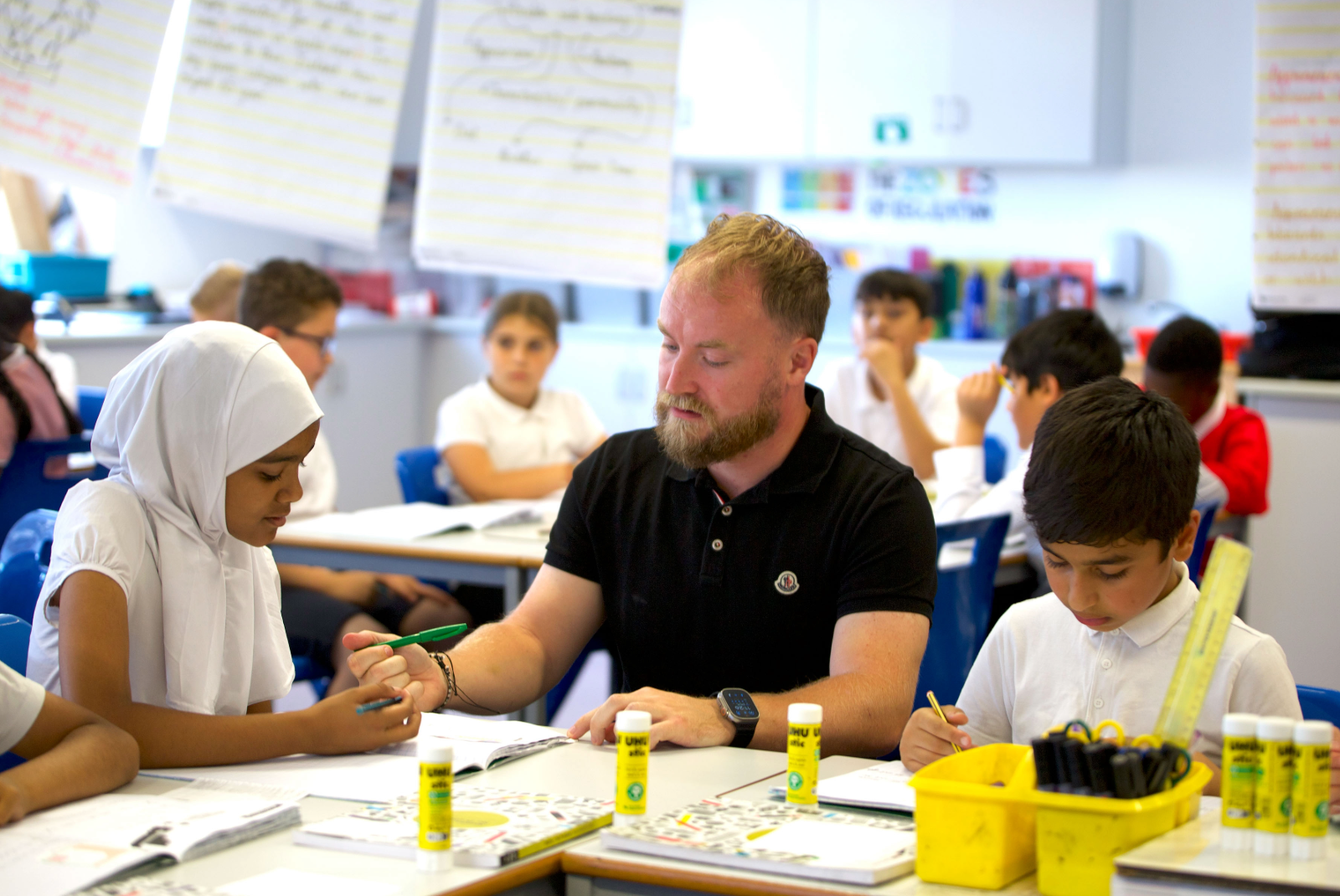 a teacher works with pupils at a table in a classroom