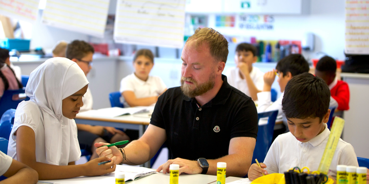 a teacher works with pupils at a table in a classroom