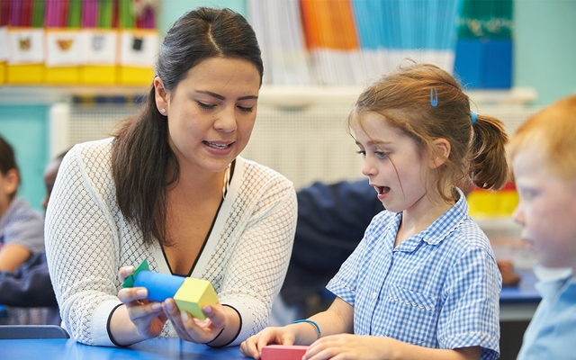Teacher helping young girl with maths.