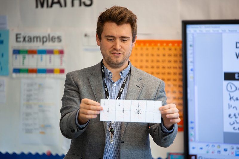 Teacher holding up number cards for students to see.