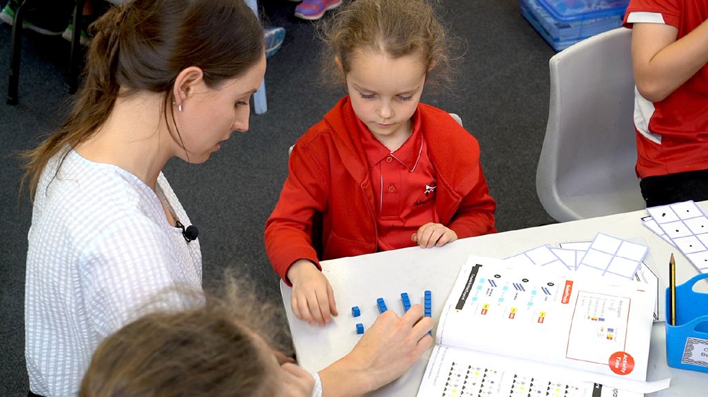 Teacher assisting pupil with manipulatives