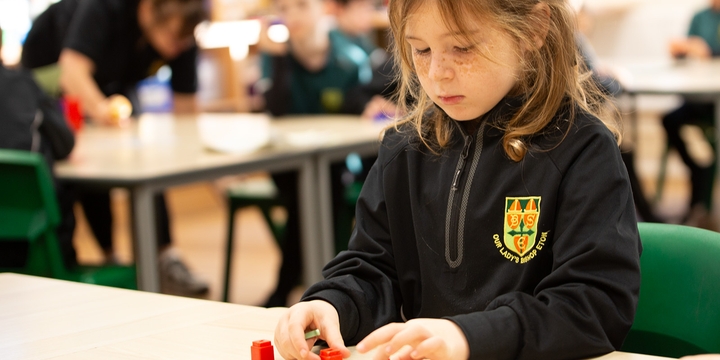 Little girl learning maths with cube manipulatives at a classroom desk.