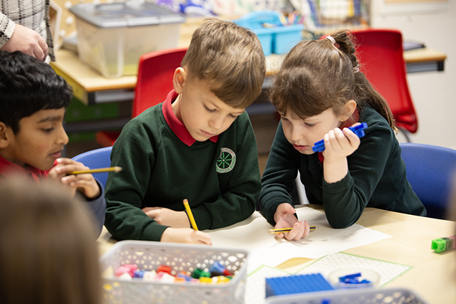 Two young pupils using working together with pencils in their hands.