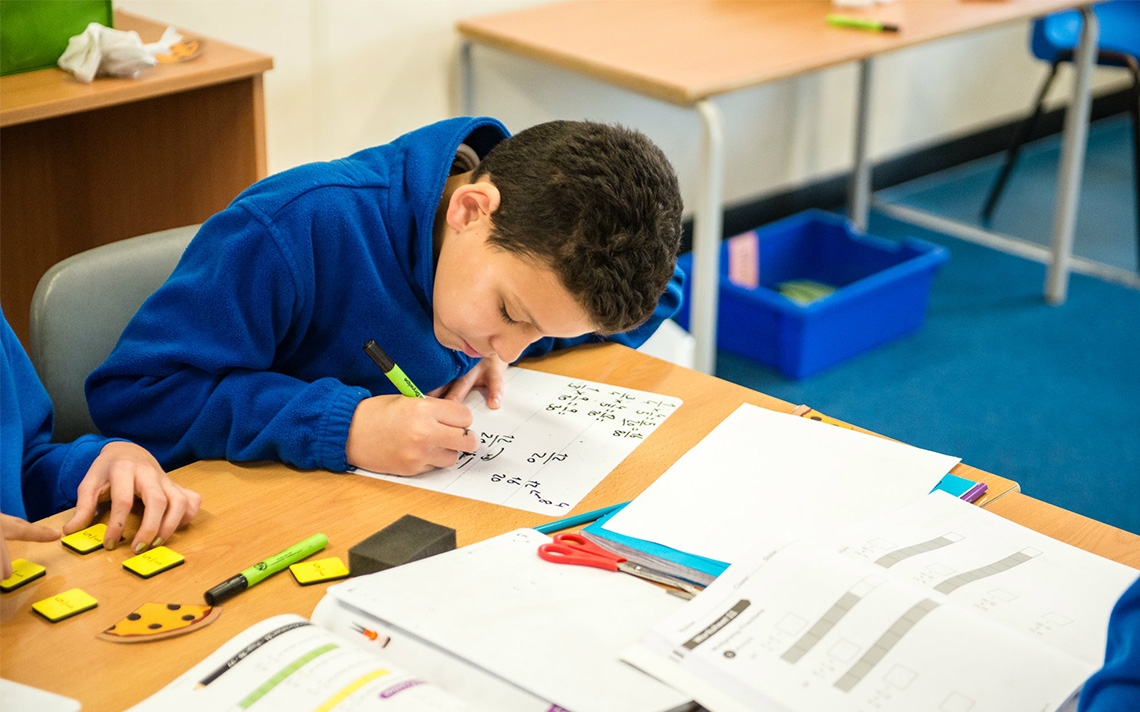 A maths student writing maths equations at a desk