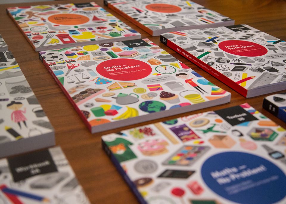 A table with Maths — No Problem! textbooks and workbooks on it