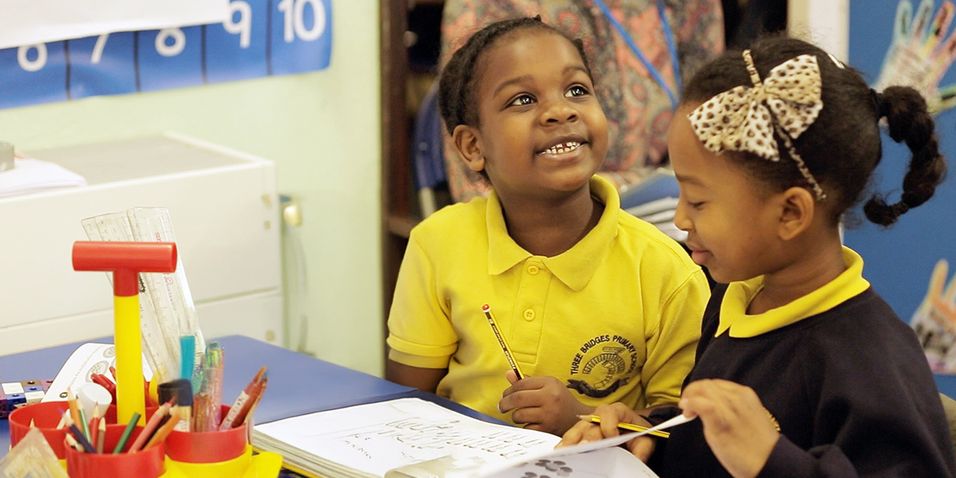 Smiling Black boy looking up while working with the Maths — No Problem! textbook with Black girl.