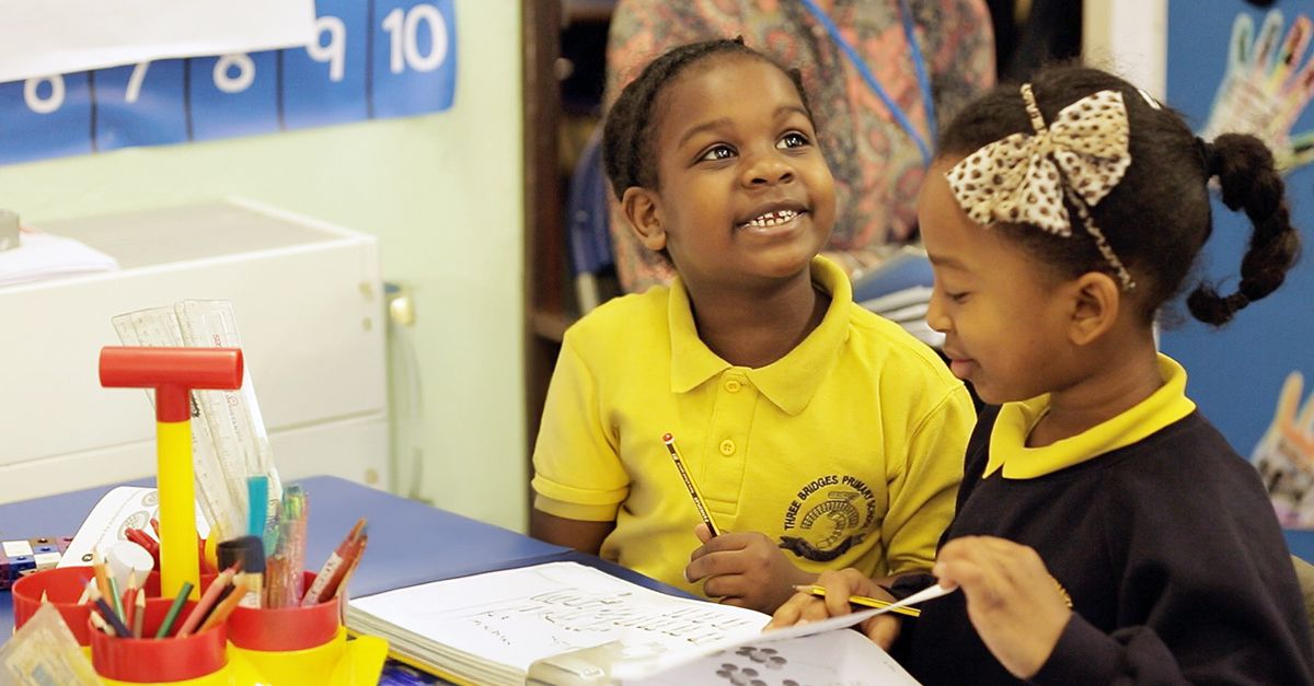 Smiling Black boy looking up while working with the Maths — No Problem! textbook with Black girl.