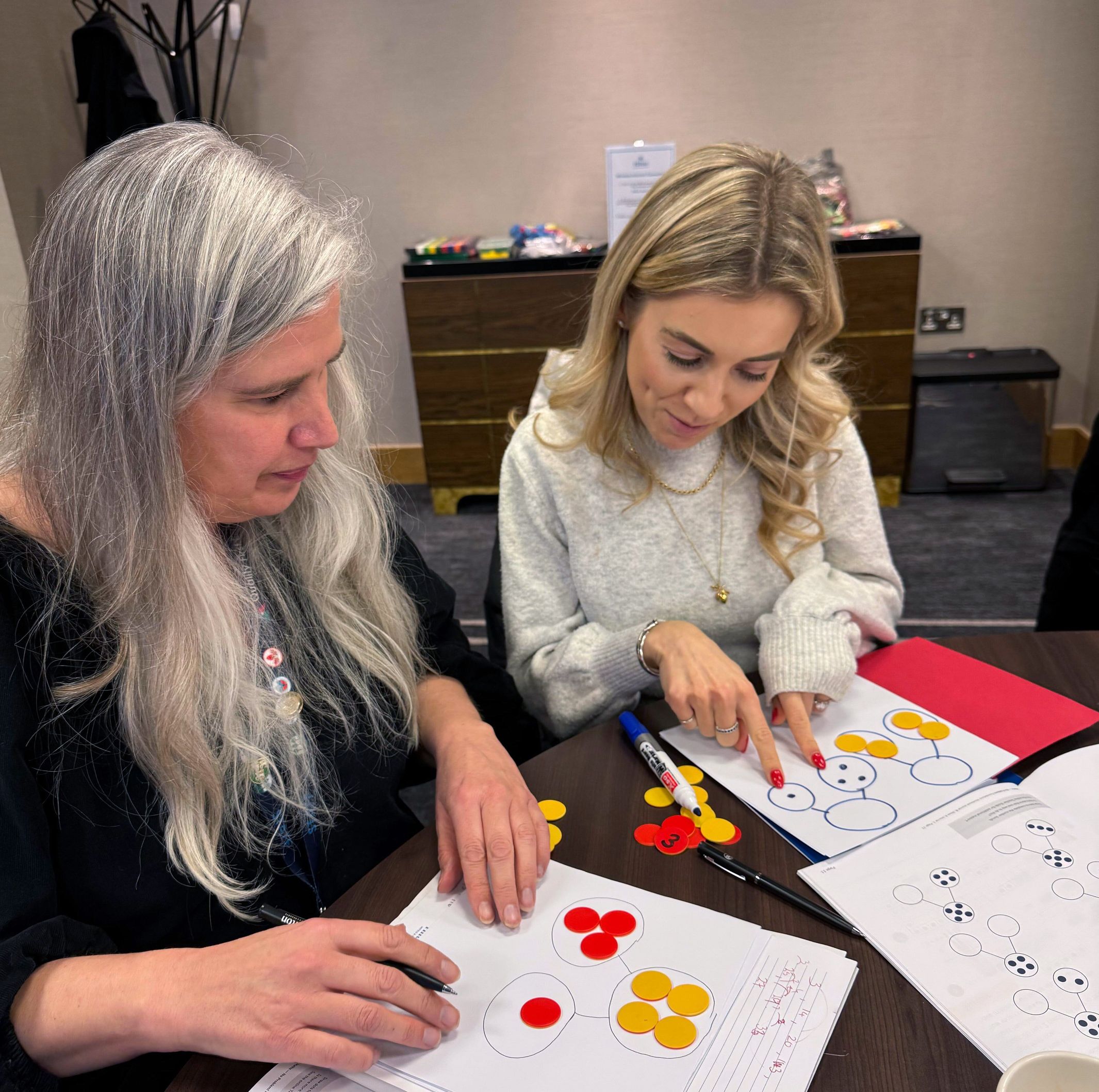 Suzi Telford speaking to teacher with manipulatives.