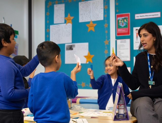 Teacher speaking to group of happy pupils.