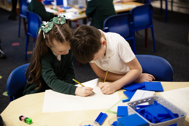 Two young pupils using working together with pencils in their hands.