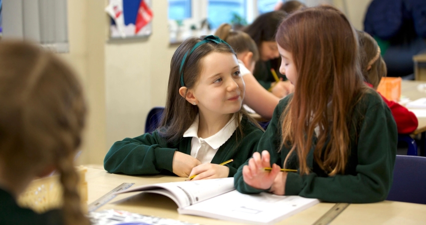 Two girls talking over a Maths — No Problem! textbook