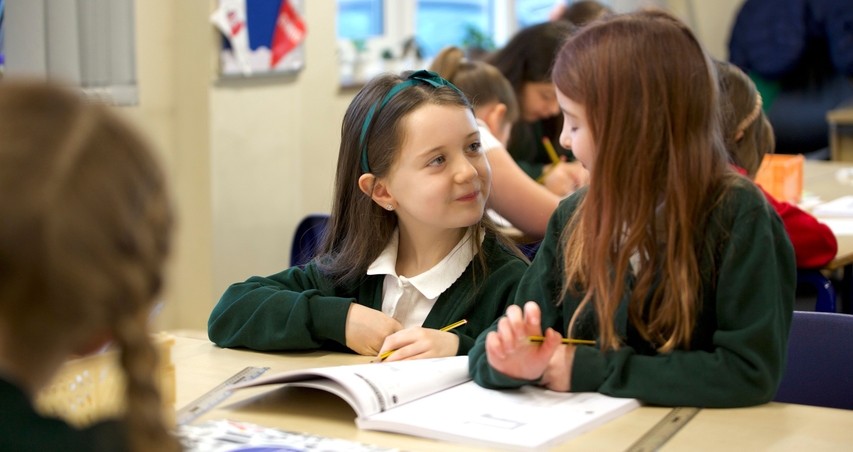 Two girls talking over a Maths — No Problem! textbook