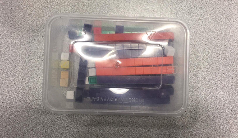 several linked and individual cubes inside a clear plastic container on a table