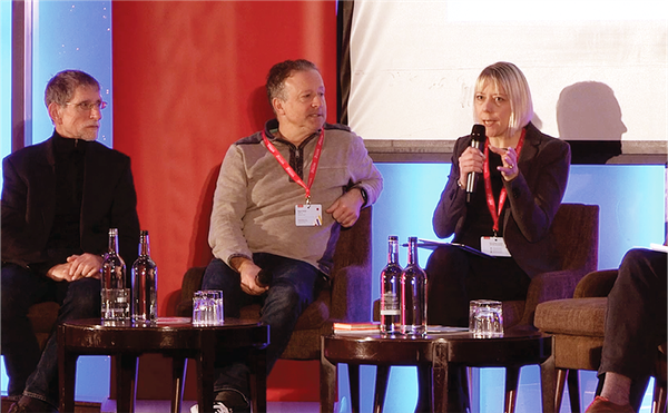 speakers talking on a panel at event