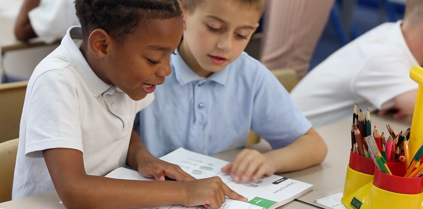 two multi-cultural primary school mathematics students using a Maths — No Problem! textbook