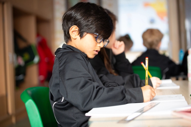 Young male student working with paper and pencil.