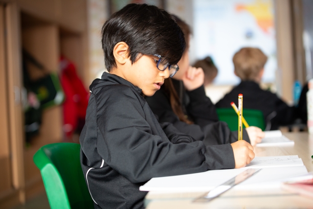 Young male student working with paper and pencil.