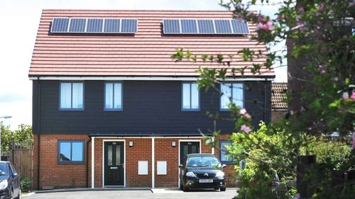 A pair of semi-detached houses with solar panels, red bricks and anthracite cladding