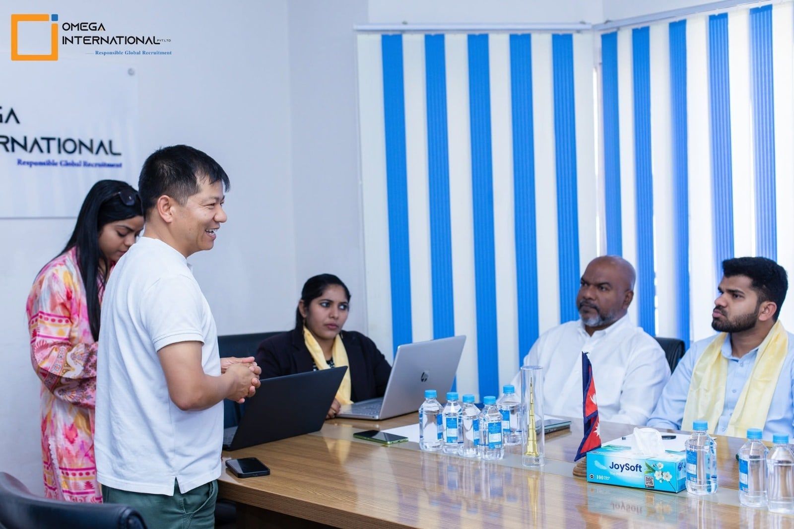 An Omega team member presenting to visiting employer partners around the meeting table at the head office