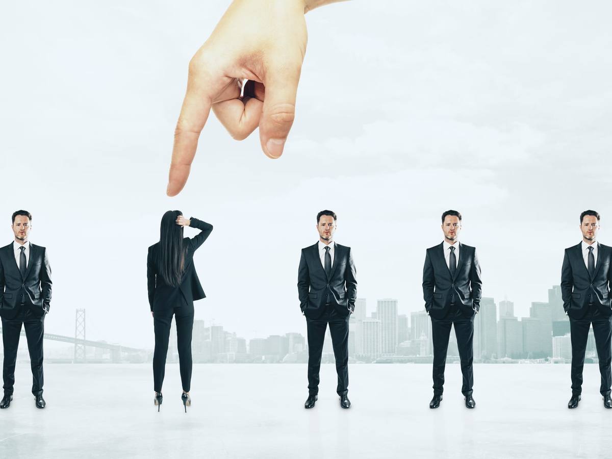 A hand pointing down to pick one person from a line of business people