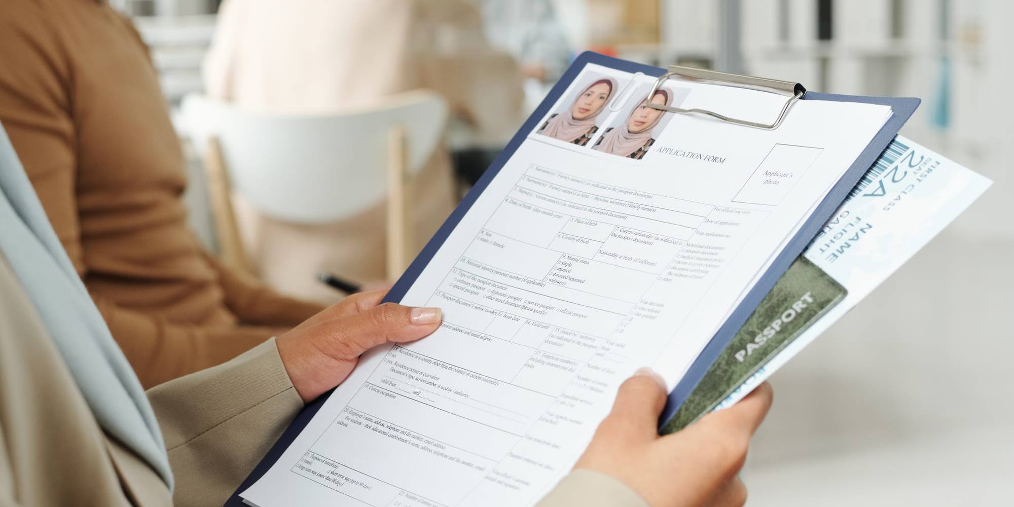 A visa application form and passport held on a clipboard