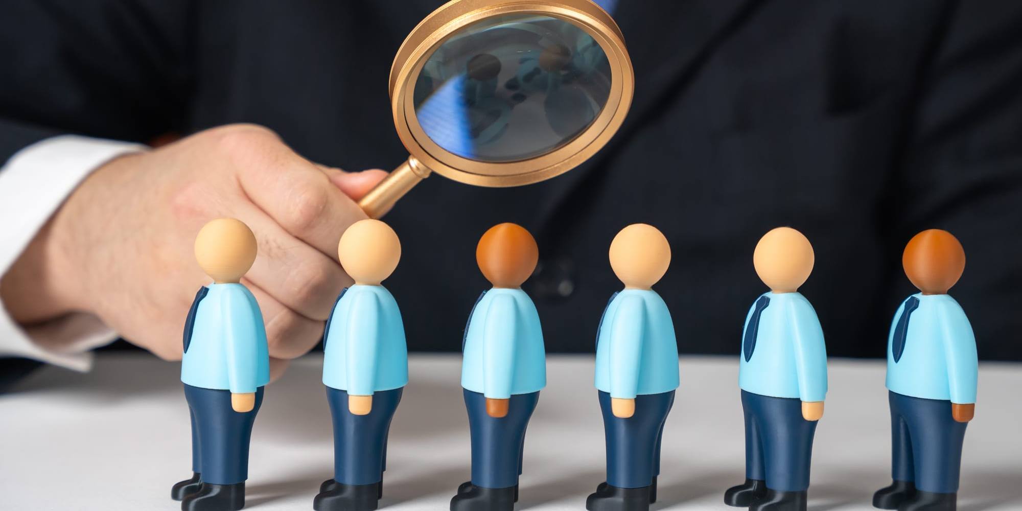 A magnifying glass held over a row of figures being screened