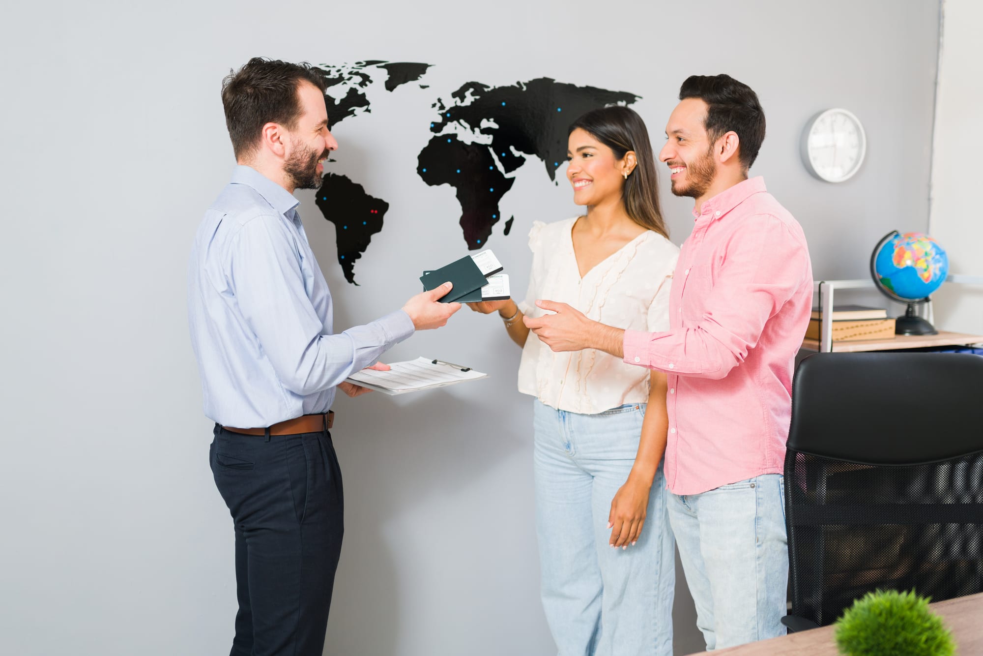 An adviser briefing two travellers in front of a world map