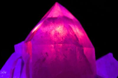 Large, glowing pink quartz crystal radiates from within while flanked by smaller purple crystals