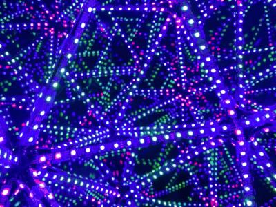 A close-up view into the octahedral infinity mirror, with dense, geometric webs of LED reflections in deep purple with hints of green and pink