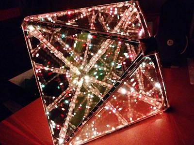Octahedral infinity mirror glowing in gold tones in a dark room