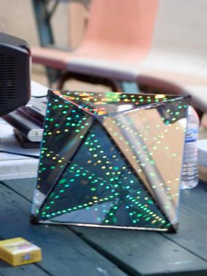 Octahedral infinity mirror sitting on a table at a party