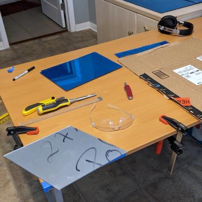 Tabletop with acrylic rhombuses and tools for scoring and cutting them from stock sheets