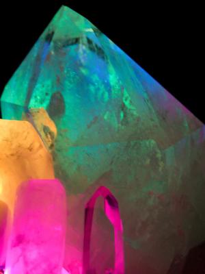 Side profile of the quartz crystal, highlighting the small transparent crystal in pink, with the large crystal glowing green