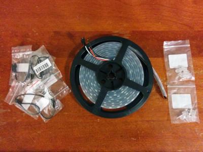 Electronics components arrays on a wooden tabletop: connectors, a spool of LEDs, and some loose LEDs in baggies