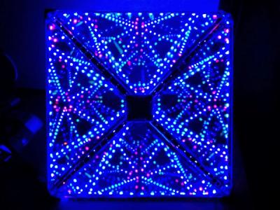 Octahedral infinity mirror glowing a deep blue with hints of purple in a dark room, viewed through one of the vertices
