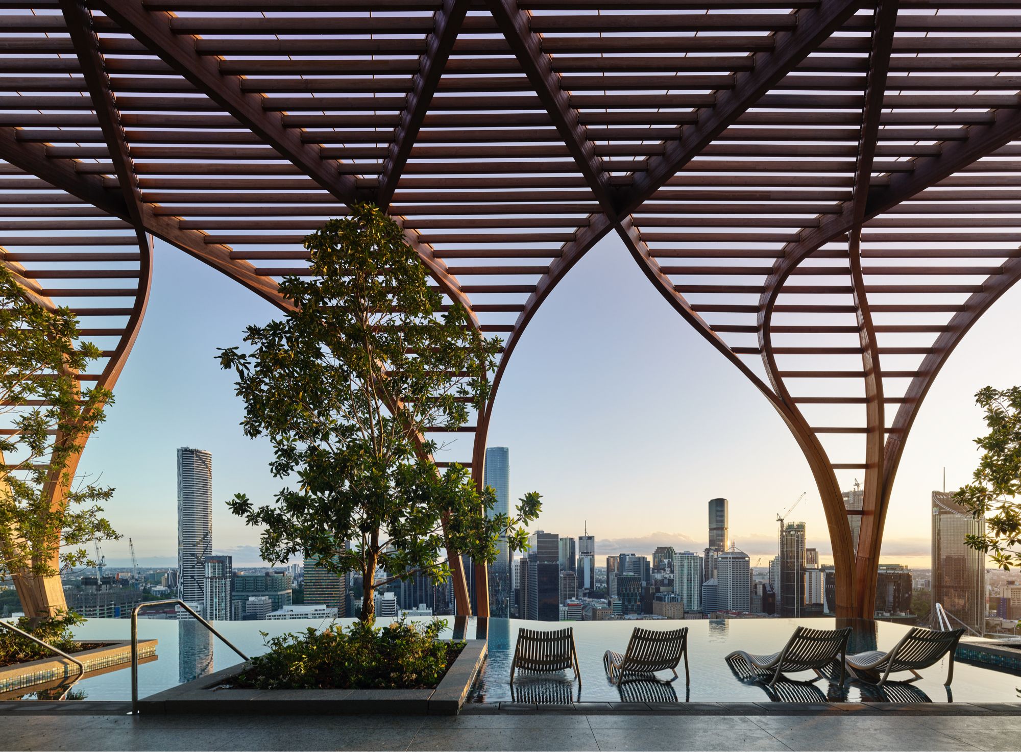 Rooftop infinity pool beneath the timber pergola at Upper House by Aria, looking to the Brisbane skyline