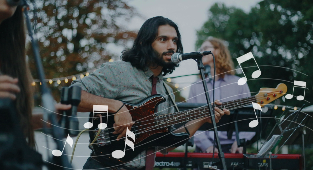 A male artist performing music, in an outdoor setting, surrounded by people appreciating the acoustics.