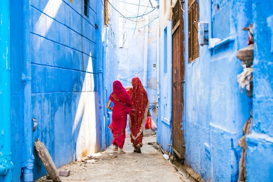 Two women dressed in the traditional Indian Saree are walking through the narrow streets of the blue city of Jodhpur, Rajasthan, India