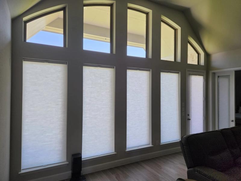 White cellular honeycomb shades on tall windows with arched transoms in a vaulted living room