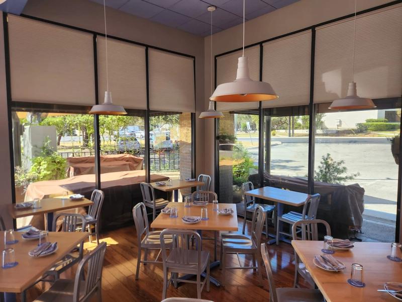 Cellular honeycomb shades on large windows in a bright restaurant dining room