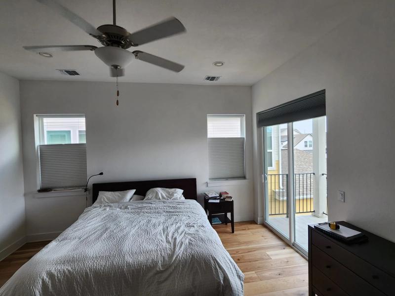 Bedroom with cellular honeycomb shades on two windows and sliding glass balcony door