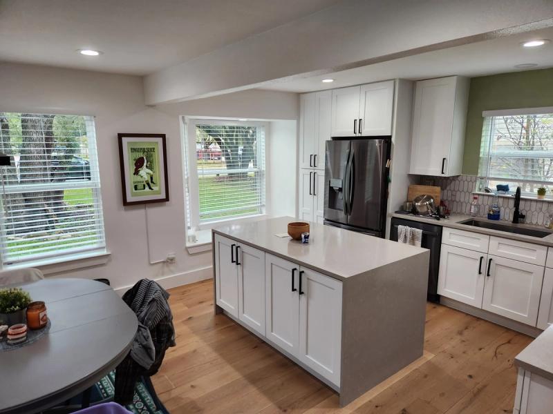Horizontal white faux-wood blinds on multiple windows in a modern white kitchen