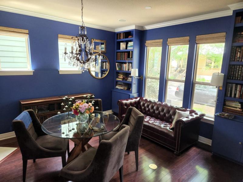 Woven wood Roman shades on multiple windows in a blue-walled living and dining room