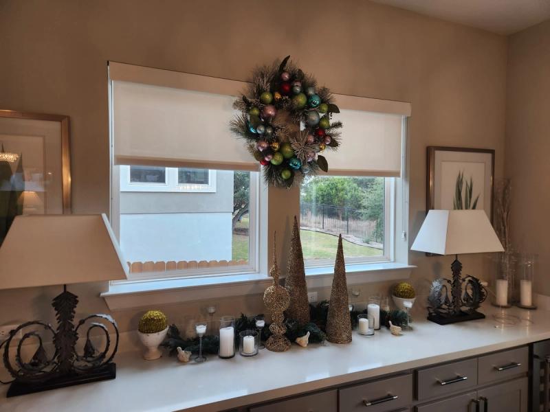 White roller shade on double window above holiday-decorated kitchen counter with wreath