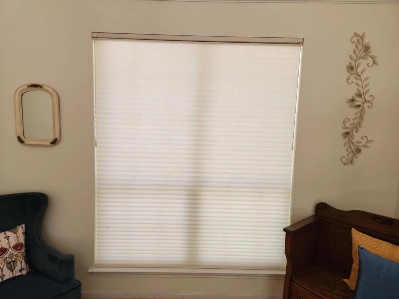 White cellular honeycomb shade fully lowered on large window in neutral living room