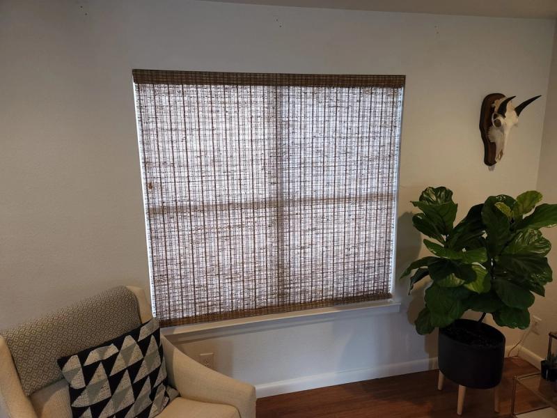 Woven wood bamboo roller shade covering large window in modern living room