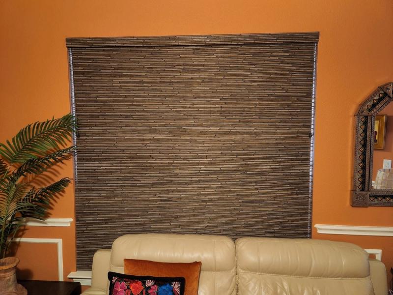Woven bamboo roman shade fully lowered over large window in orange living room