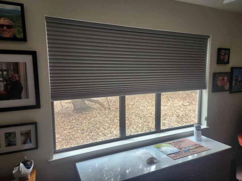 Gray cellular honeycomb shade partially lowered on wide three-panel window in home interior